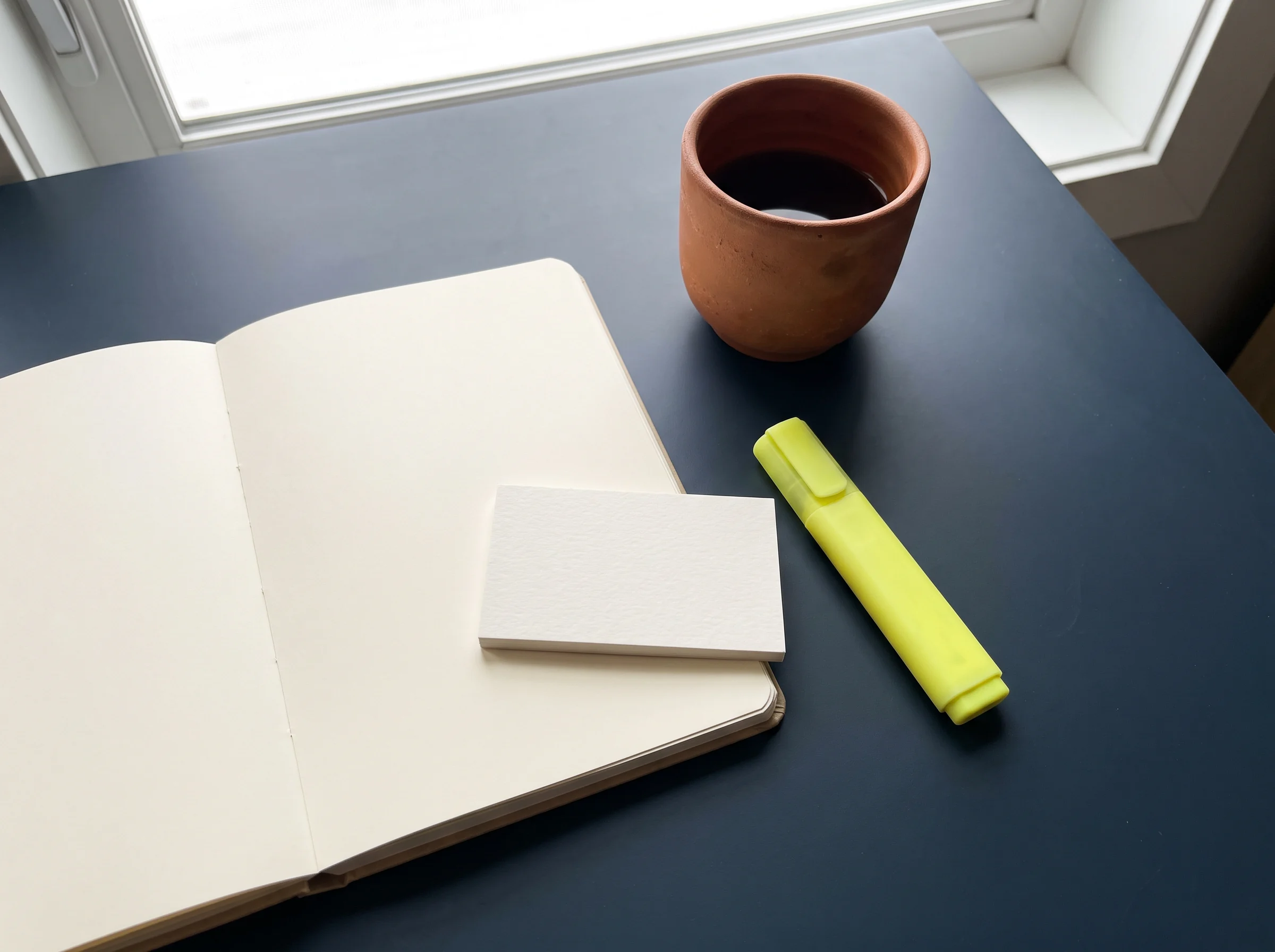 An open notebook and highlighter by a cup of coffee